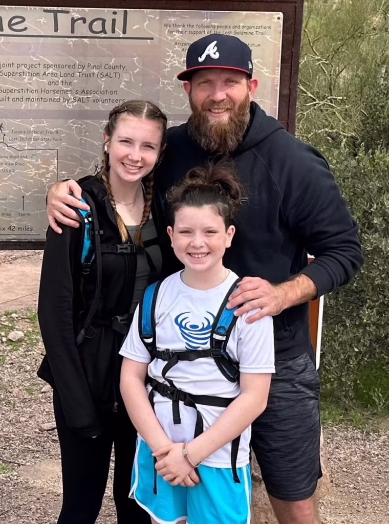 John Immke, Co-owner of Invictus smiling outdoors with two children in a casual family photo