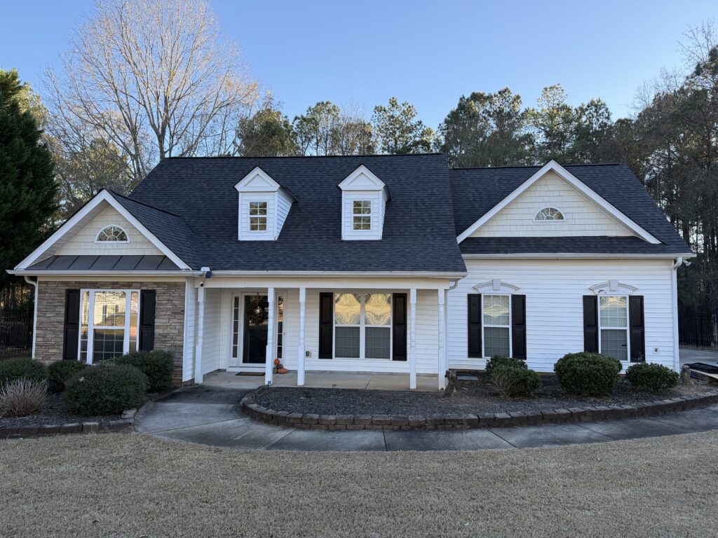 White home with dark asphalt shingle roof installed by a certified roofing contractor for stronger manufacturer warranty coverage.
