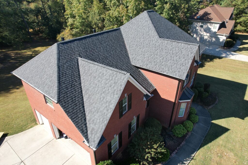 Aerial view of a large brick property with a new gray shingle roof installed by Invictus, a licensed Tennessee general contractor and roofing contractor.