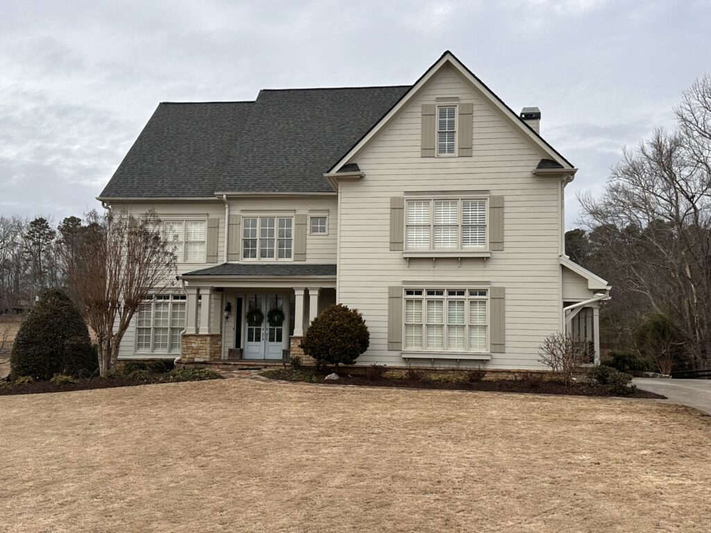 Large two-story home with a dark shingle roof, representing residential work by a certified roofing contractor.