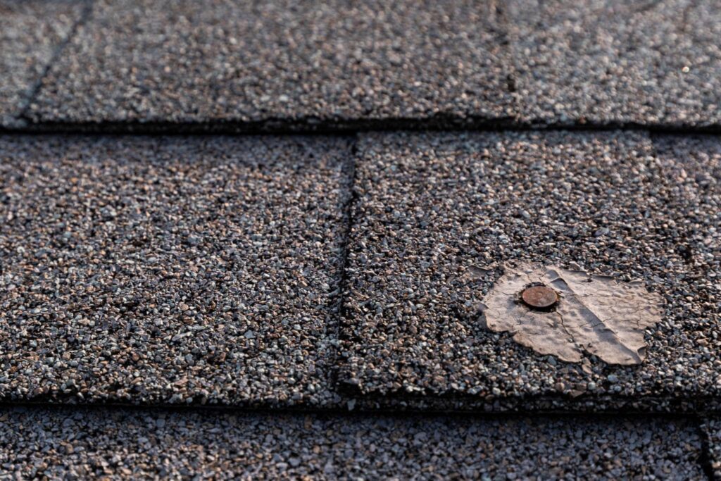 Close-up of asphalt shingle roof repair in Woodstock, GA showing damaged roofing shingle and exposed nail sealant detail